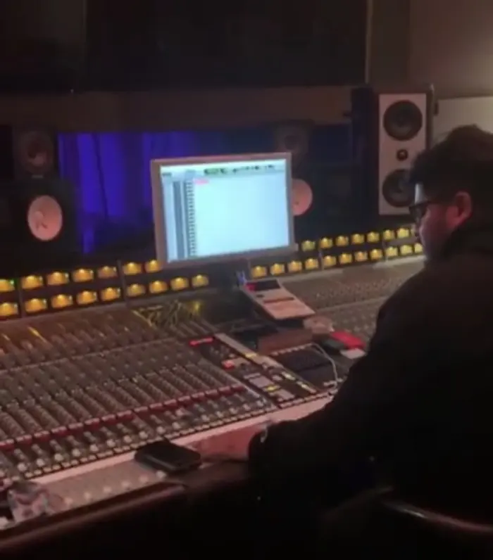 Engineer Jorge Hernandez at a large analog mixing console in a studio control room, monitors and a session on screen