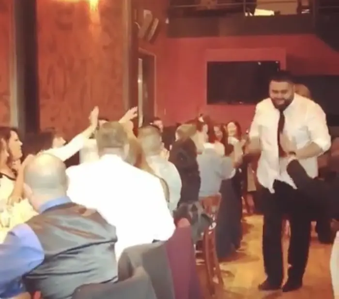 MC Solar Wind in a white shirt and tie walking through a dinner crowd with hands raised